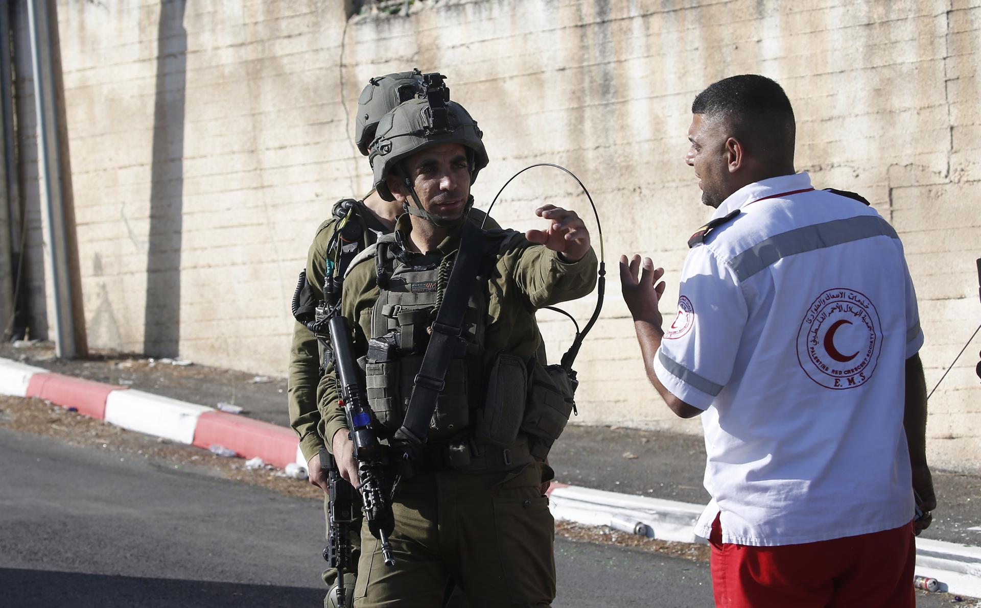 A soldier speaks with a Red Crescent medic near the area where three Palestinians were shot near the West Bank city of Nablus, 25 July 2023. EFE-EPA/ALAA BADARNEH