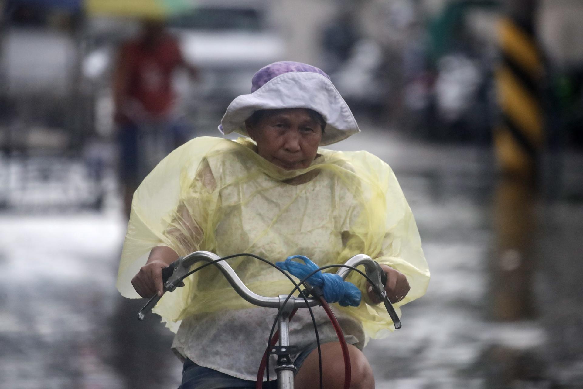 A Filipino woman rides a bicycle along a street covered by floodwater in Malabon city, Metro Manila, Philippines, 26 July 2023. EFE-EPA/FRANCIS R. MALASIG