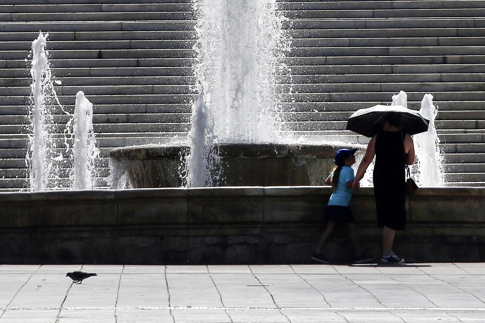 A woman and a child walk past a fountain as they make their way through central Syntagma square amidst high temperatures, in Athens, Greece, 22 July 2023. EFE/EPA/ORESTIS PANAGIOTOU
