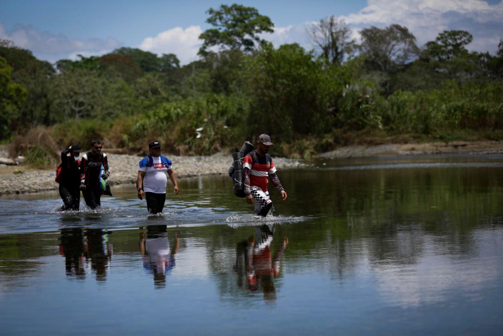 Personas migrantes cruzan el río Tuquesa, en Darién (Panamá). EFE/Bienvenido Velasco
