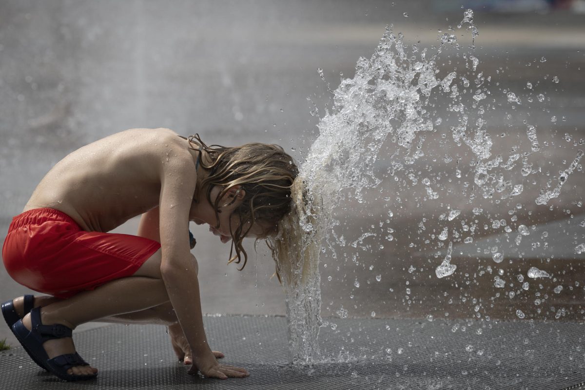 Un niño se refresca en una fuente de Pamplona.