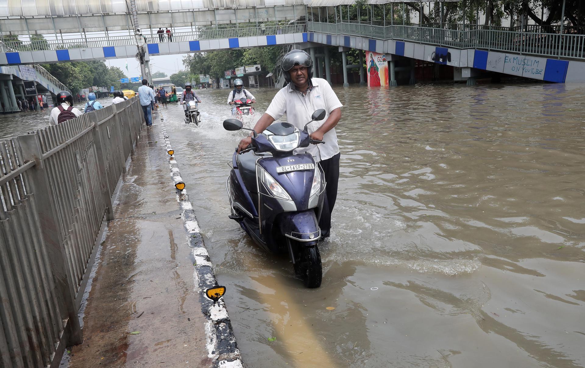 A man pushes his motorbike trying to cross a flooded street as the Yamuna river is flowing over its danger mark, in New Delhi, India, 14 July 2023. EFE/EPA/HARISH TYAGI