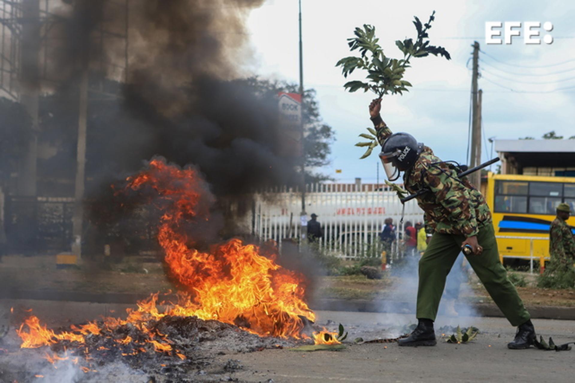 A Kenyan police officer tries to put out fire set by protesters during a rally against tax increases in Nairobi on 7 July 2023. EFE/EPA/STRINGER
