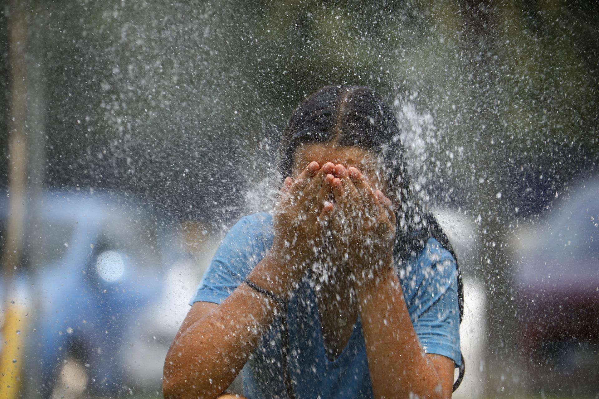 Una joven se refresca en una fuente de una calle de Córdoba durante la primera ola de calor que afectó a España este verano. EFE/Salas
