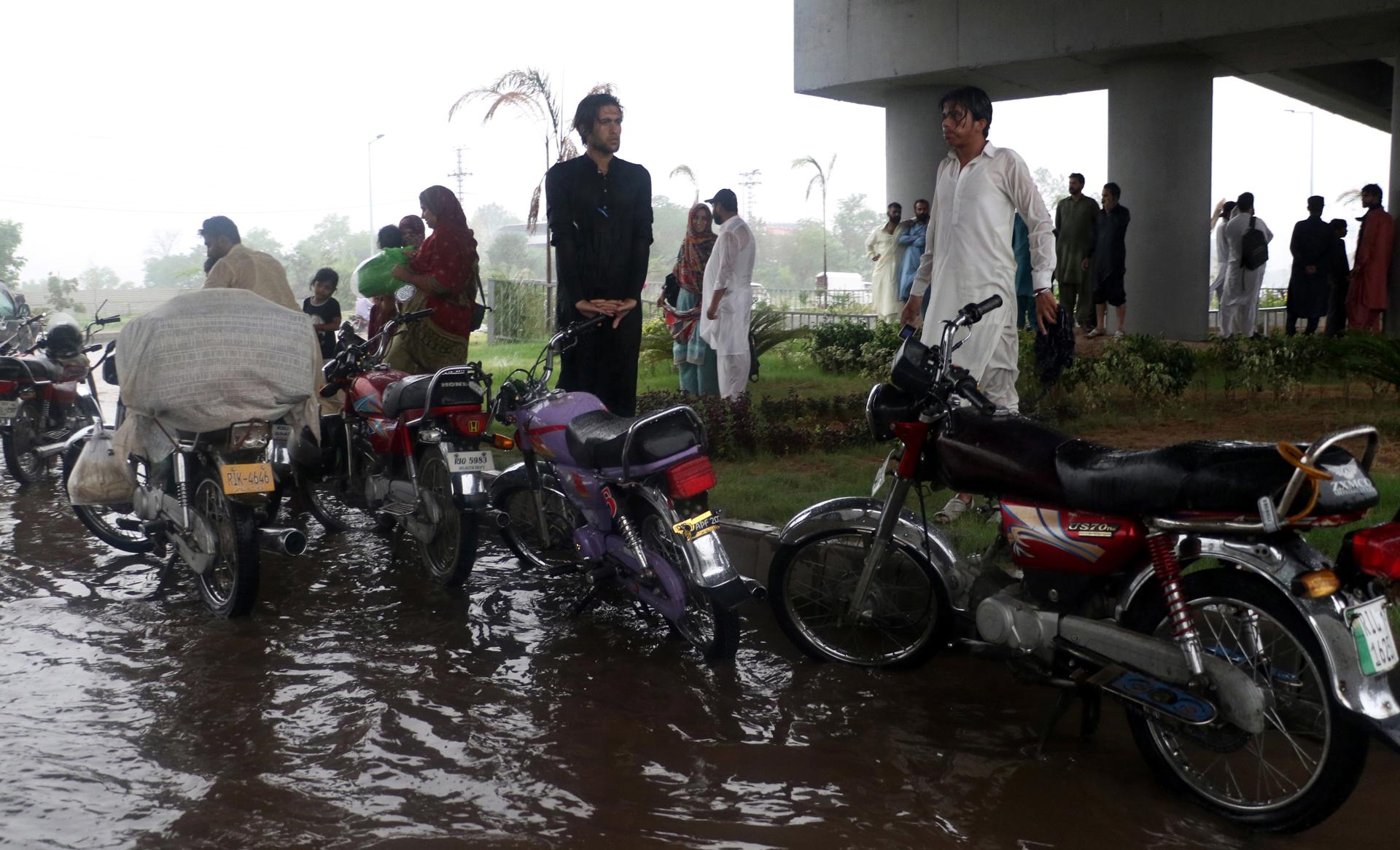 People stand under a bridge during heavy monsoon rain in Islamabad, Pakistan, 14 July 2023. EFE-EPA/FILE/SOHAIL SHAHZAD