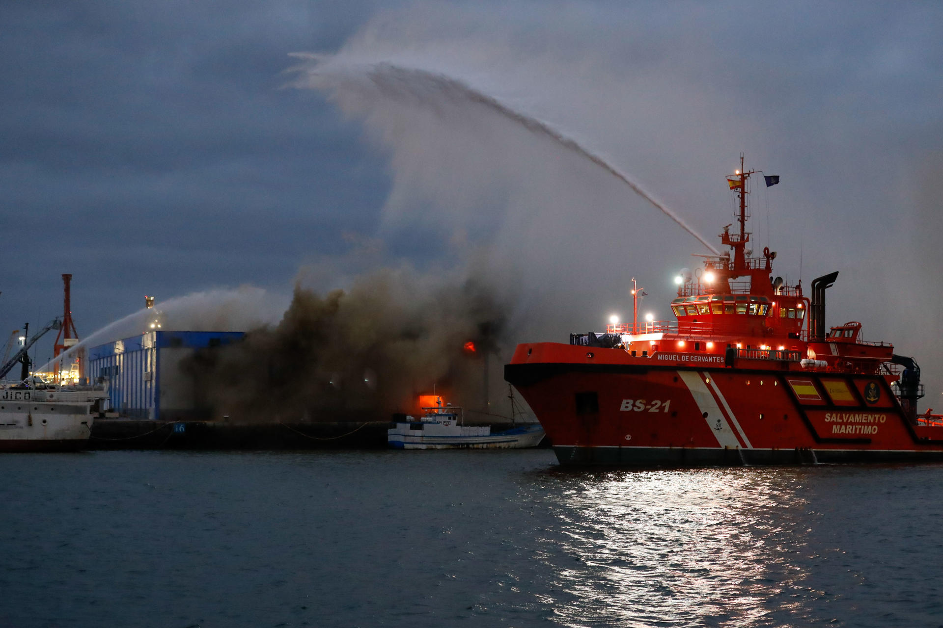 Equipos de bomberos combaten por mar y tierra un incendio declarado este jueves en una nave frigorífica del muelle pesquero del puerto de Las Palmas de Gran Canaria. EFE/ Elvira Urquijo A.