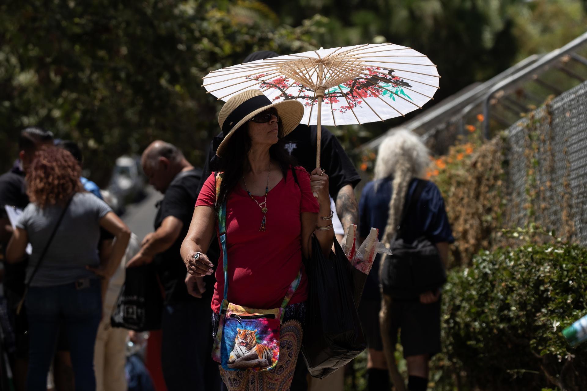 Una mujer se protege ante el sol y las altas temperaturas en el Echo Park de Los Ángeles, California, el 15 de julio de 2023. EFE/Etienne Laurent