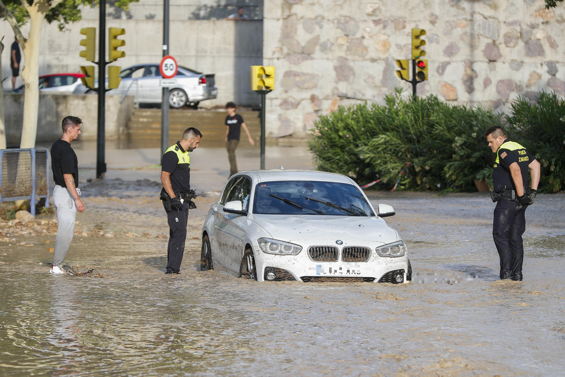 Agentes de la Policía Local observan un coche arrastrado por la tormenta caída este jueves en Zaragoza. EFE/Javier Cebollada
