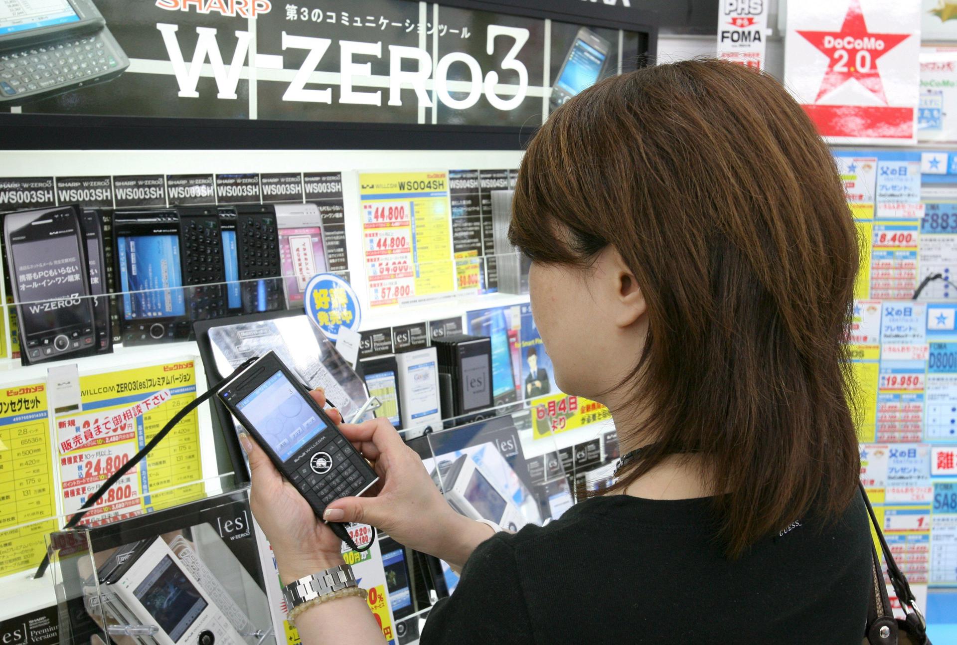 A consumer shops for multifunctional handset, or 'smart phone,' on display at an electronics store in downtown Tokyo, Japan 11 June 2007. EPA/FILE/EVERETT KENNEDY BROWN
