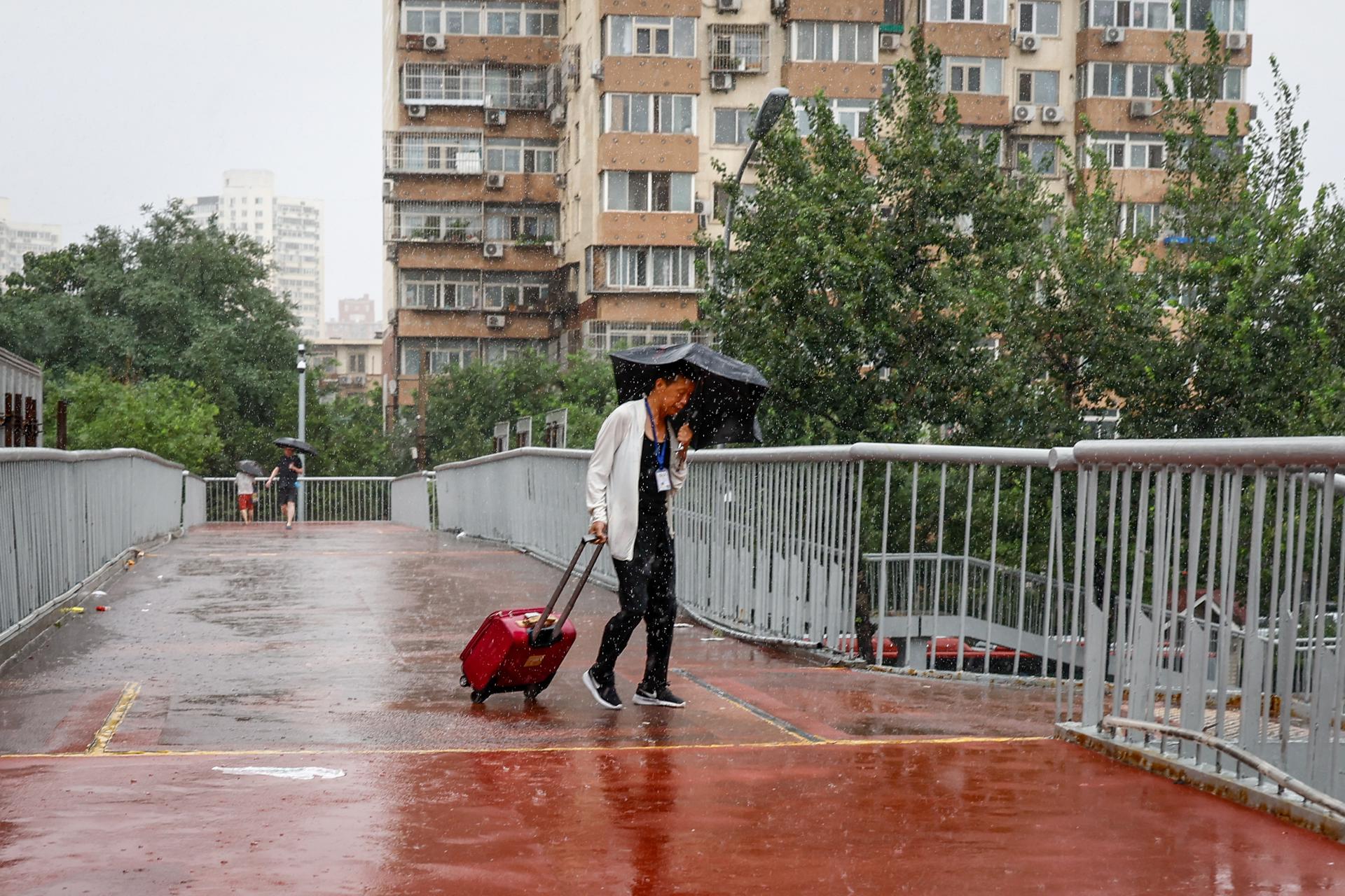 A man uses an umbrella during a downpour in Beijing, China, 30 July 2023. EFE-EPA/MARK R. CRISTINO
