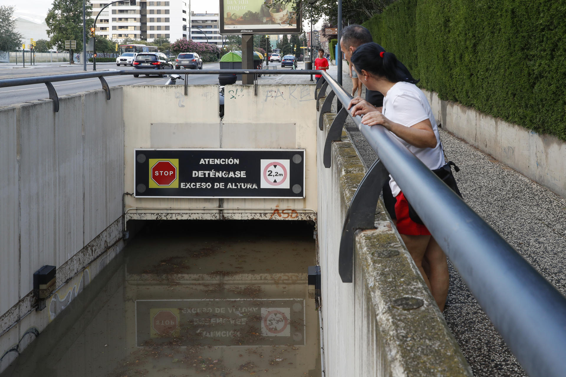 Dos personas observan el nivel alcanzado por el agua, de casi dos metros de altura, en un paso subterráneo este jueves en Zaragoza. EFE/Javier Belver
