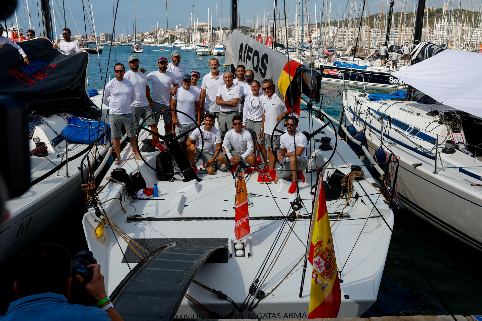 El rey Felipe VI posa junto a la tripulación a bordo del "Aifos" de la Armada Española al comienzo de la primera jornada de la Copa del Rey de vela, este lunes, en Palma.EFE/ Ballesteros
