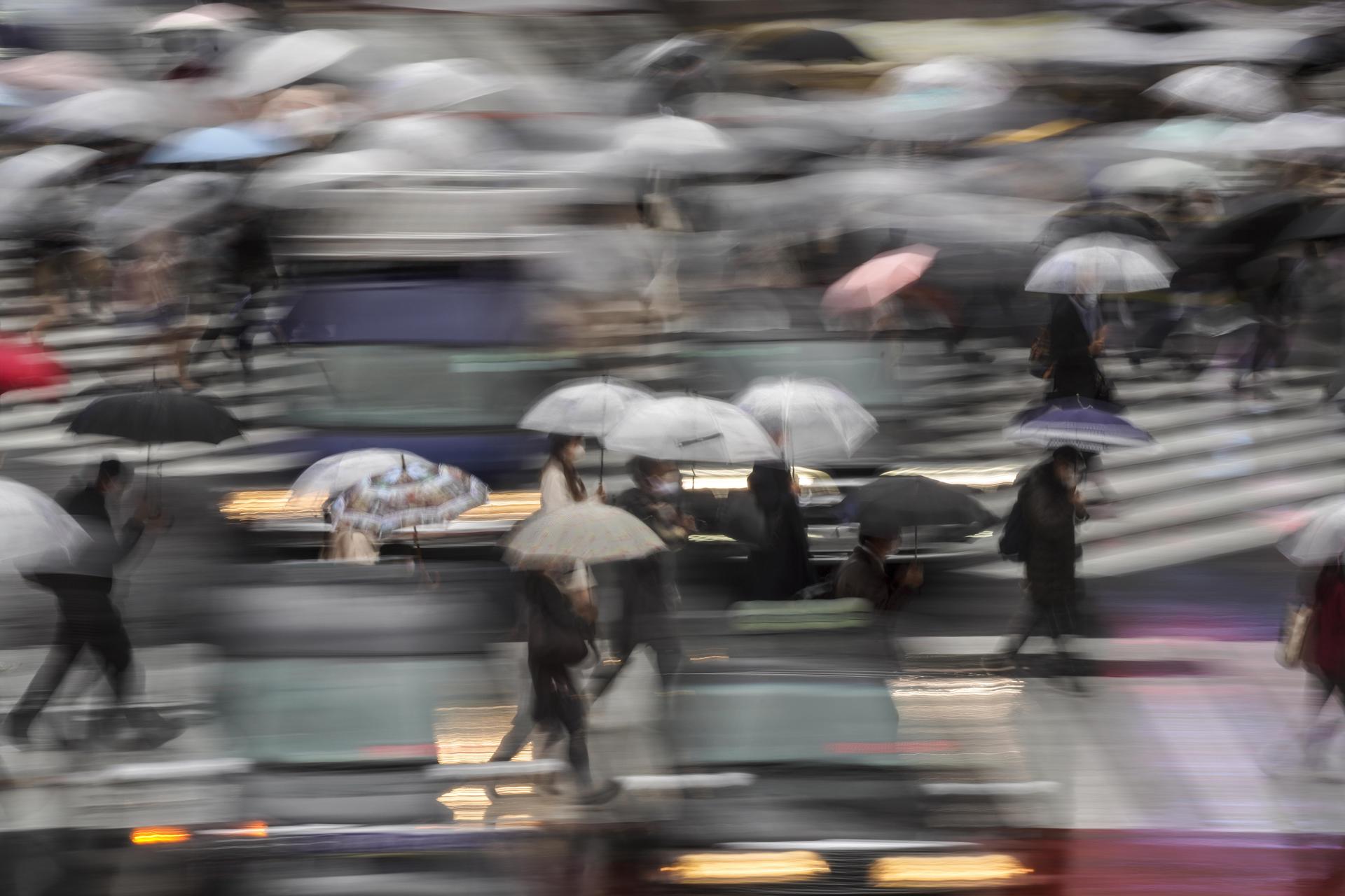 A picture made with a slow shutter speed shows pedestrians using umbrellas while walking through a crosswalk in Tokyo, Japan, 09 October 2020. EFE-EPA FILE/KIMIMASA MAYAMA