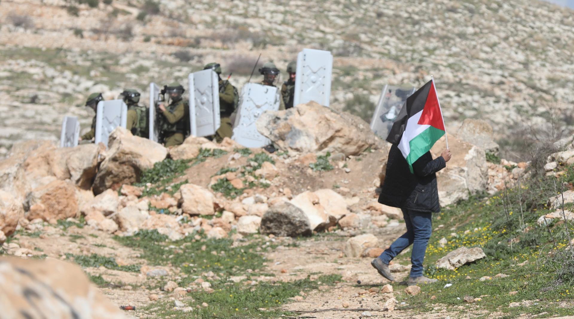 A Palestinian waves a Palestine flag during clashes with Israeli soldiers after a protest at Bet Dajan village near the West Bank city of Nablus, 24 February 2023. EFE-EPA FILE/ALAA BADARNEH