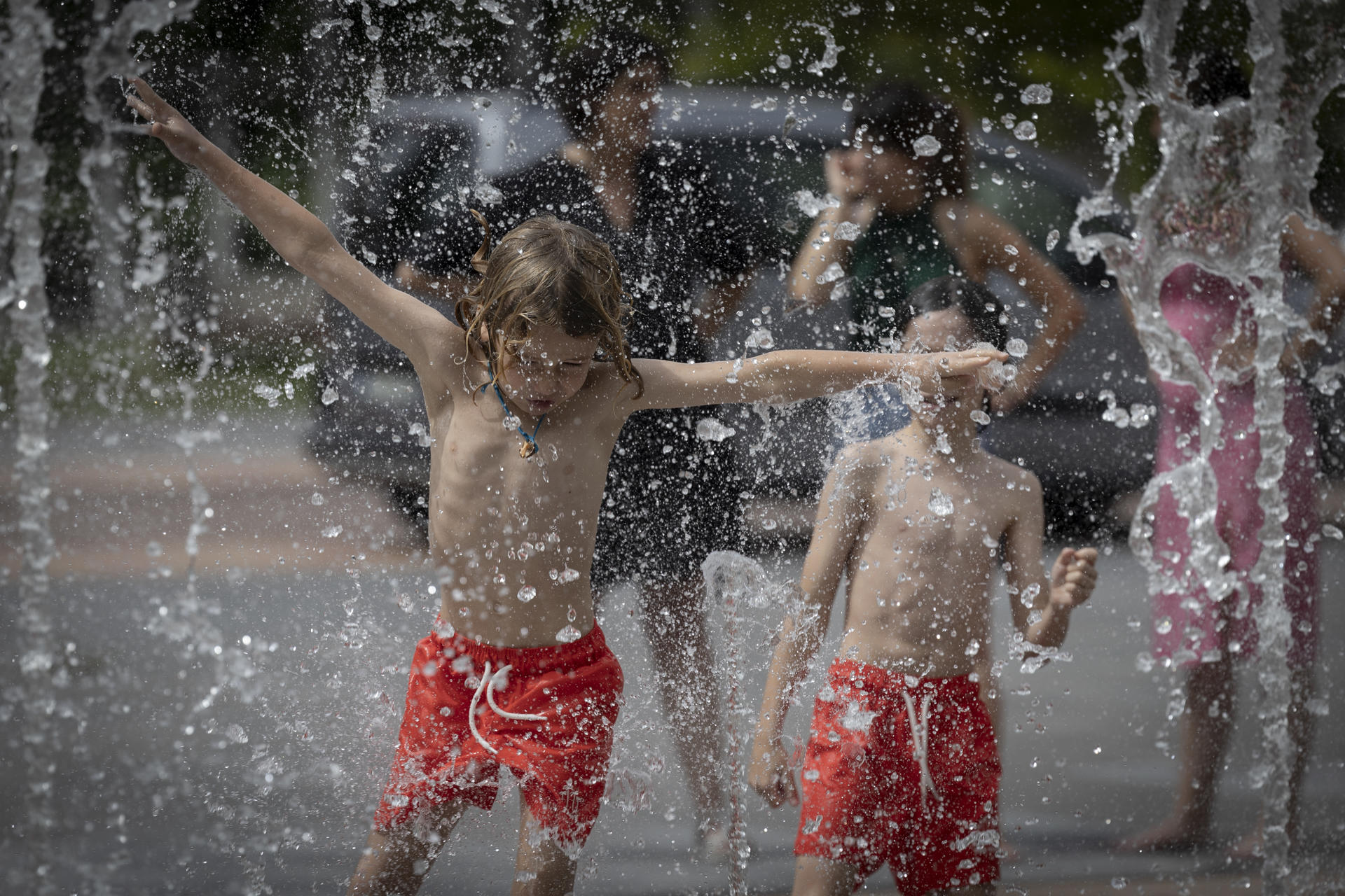 Varios niños se divierten a la vez que se refrescan en una fuente de Pamplona. EFE/ Villar López