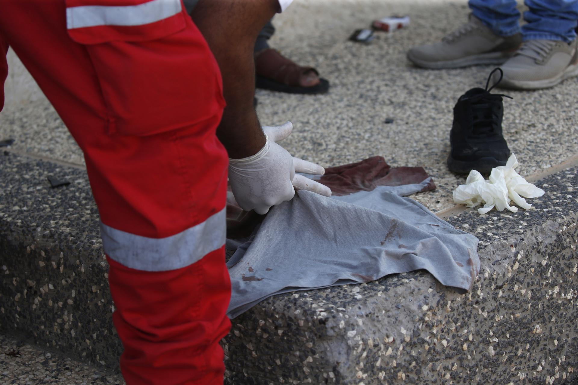 A person collects blood-stained clothes at the area where three Palestinians were shot near the West Bank city of Nablus, 25 July 2023. EFE-EPA/ALAA BADARNEH

