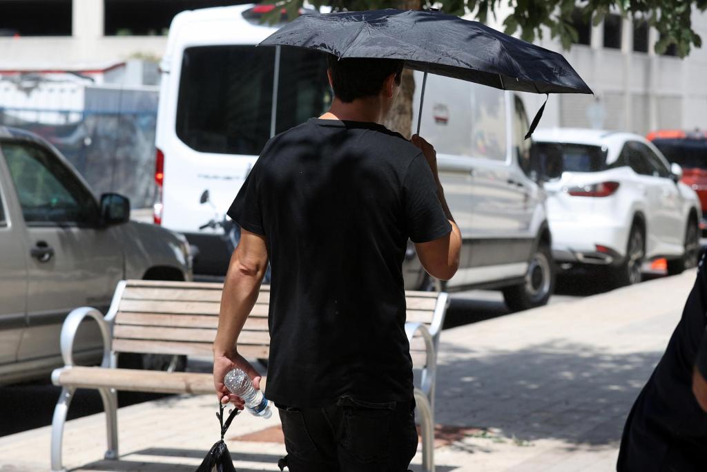Un hombre se protege del sol en una calle de Austin, Texas, el 16 de julio de 2023. EFE/Adam Davis
