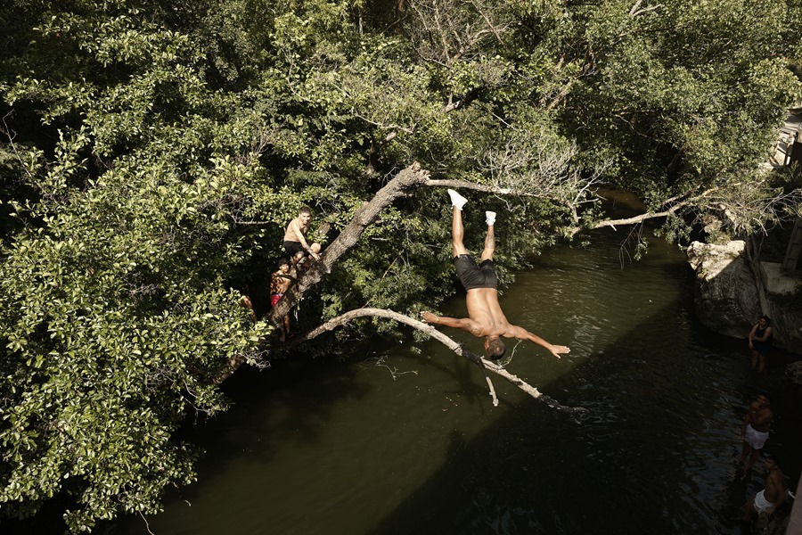 Una persona se tira desde un árbol al agua del rio Arga a su paso por la localidad de Iroz