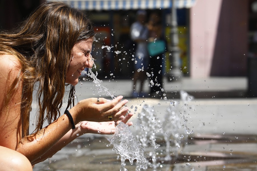 Una mujer se refresca en una de las fuentes del centro de Córdoba donde se ha dado aviso naranja por altas temperaturas.