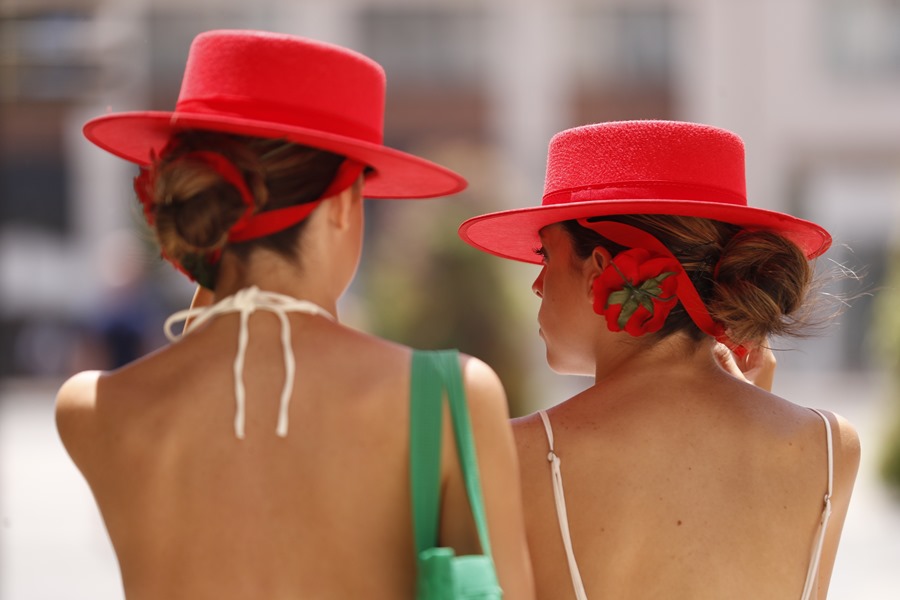 Dos jóvenes caminan por el centro de Málaga con sombreros para resguardarse del sol