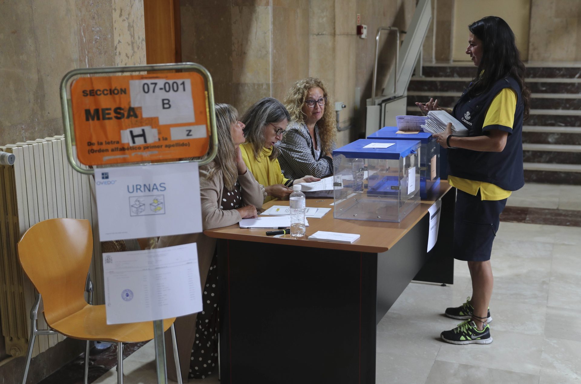 Una cartera deposita los votos por correo de las elecciones generales en un colegio electoral en Oviedo.