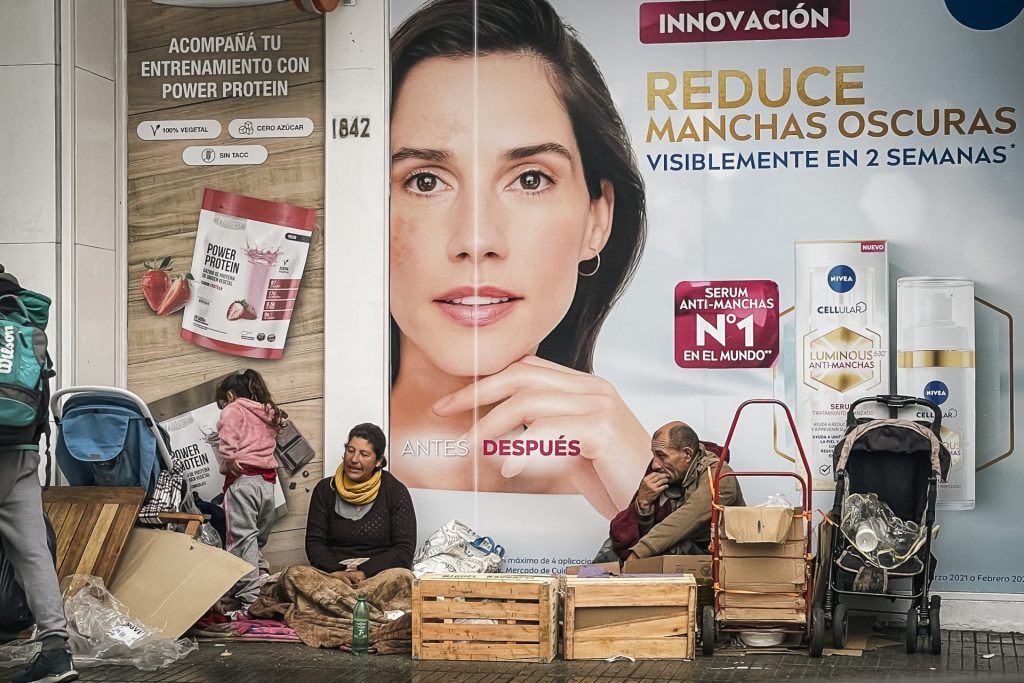 Personas en condición de calle permanecen junto a sus pertenencias frente a una tienda de cosméticos, el 17 de agosto de 2023, en Buenos Aires (Argentina). EFE/Juan Ignacio Roncoroni