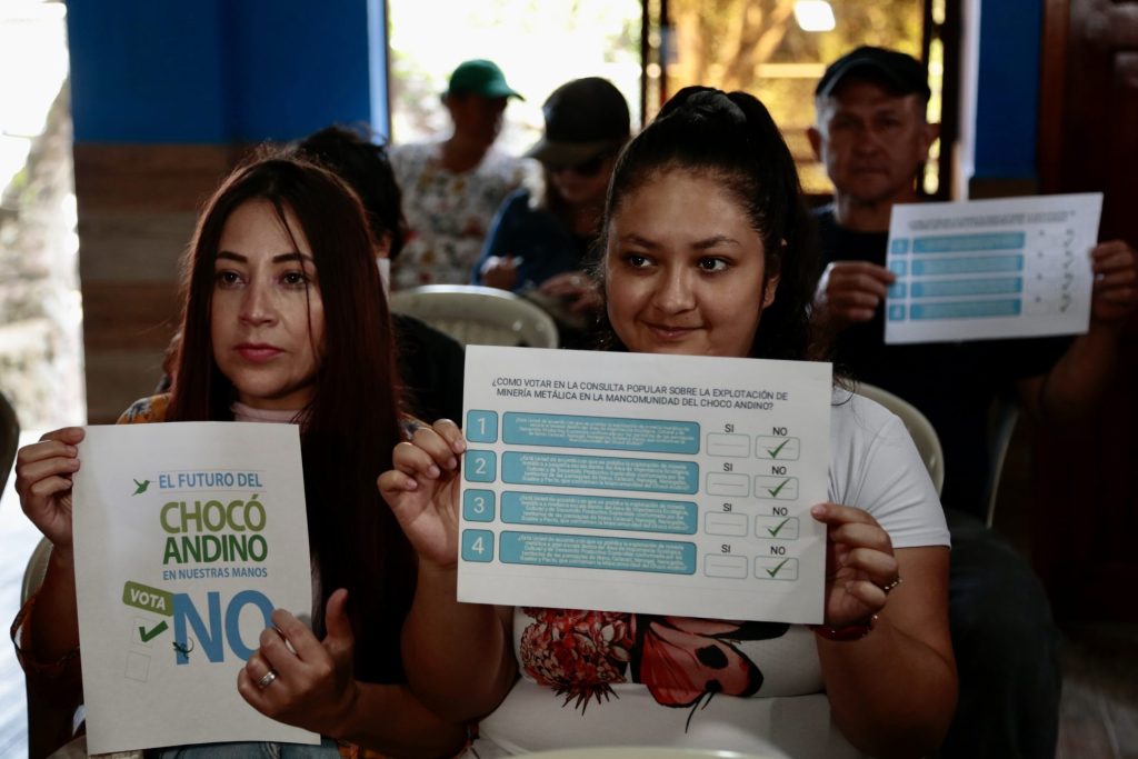 Habitantes sostienen un cartel para votar por el "No" en el plebiscito que propone prohibir la minería legal en el Chocó Andino, el 4 de agosto de 2023, en la localidad rural de Pacto (Ecuador). EFE/Santiago Fernández