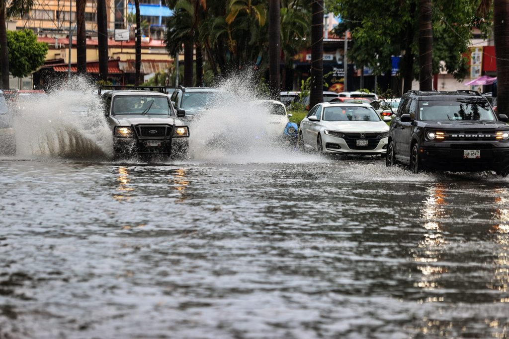 Vehículos transitan por una calle inundada debido a las fuertes lluvias, el 16 de agosto de 2023, en el balneario de Acapulco, estado de Guerrero (México). EFE/David Guzmán