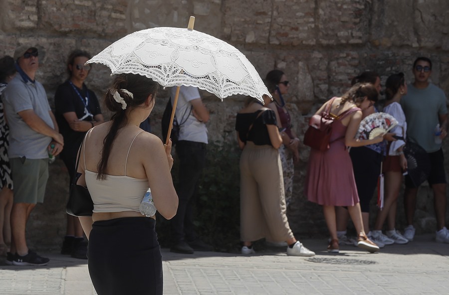  Unos turistas esperan en el trozo de sombra para entrar al Real Alcázar de Sevilla