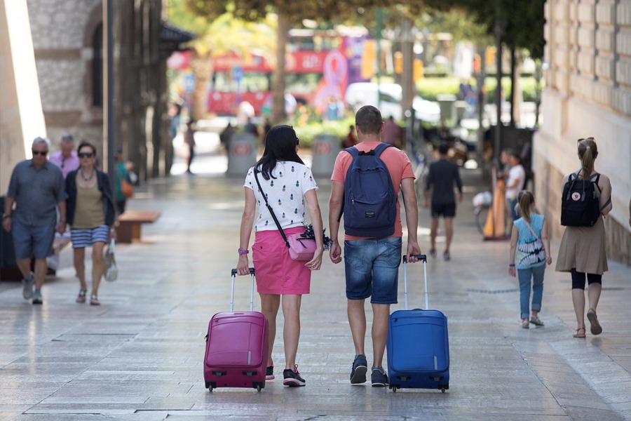 Varios turistas con sus equipajes caminan por el centro de Málaga