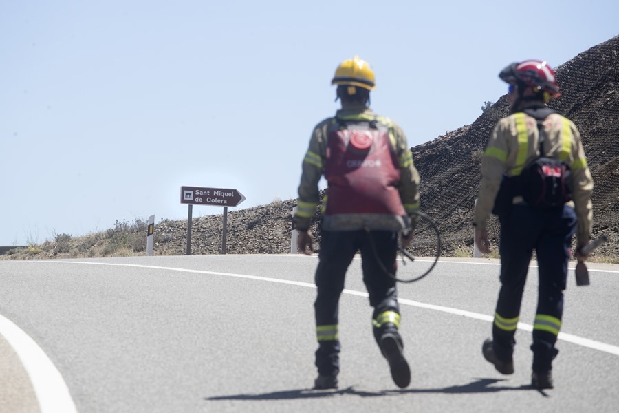 Dos bomberos caminan por una de las zonas afectadas por el incendio en Portbou (Girona).
