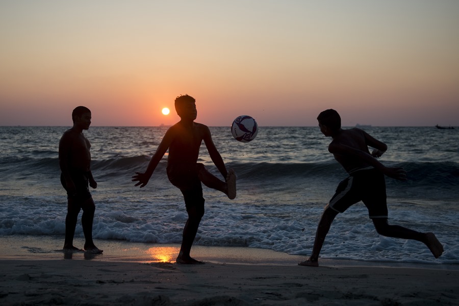 Niños juegan con un balón durante en la playa. 