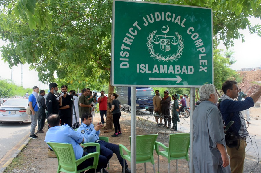 Policía y periodista fuera del complejo judicial donde un tribunal condenó a Imran Khan, ex primer ministro de Pakistan. E