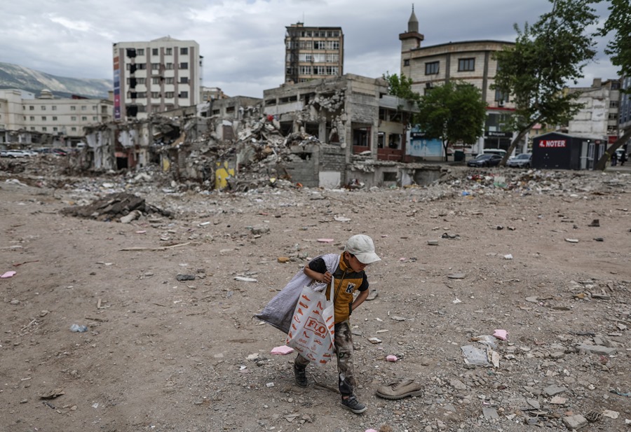 Un niño junto a edificios destruidos en el terremoto de Turquía.