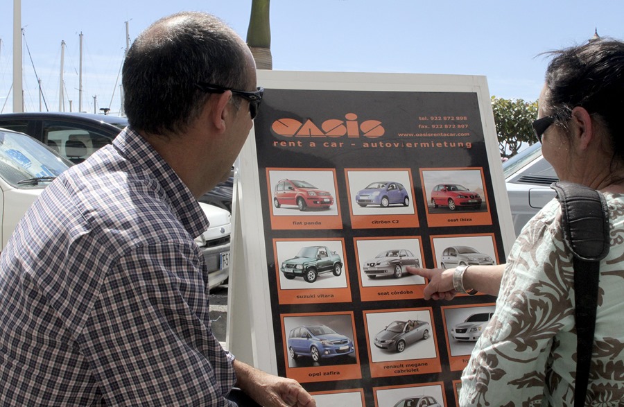 Un empleado de una empresa de alquiler de coches muestra a una clienta los vehículos disponibles