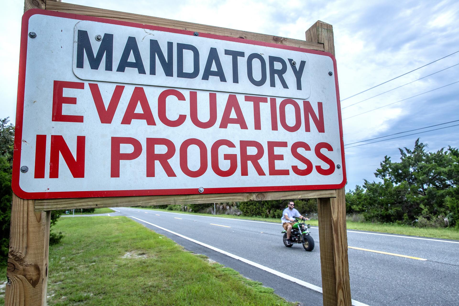 A person rides a bike near a 'mandatory evacuation' sign, as the town prepares for Hurricane Idalia, in Cedar Key, Florida, US, 29 August 2023. EFE-EPA/CRISTOBAL HERRERA-ULASHKEVICH
