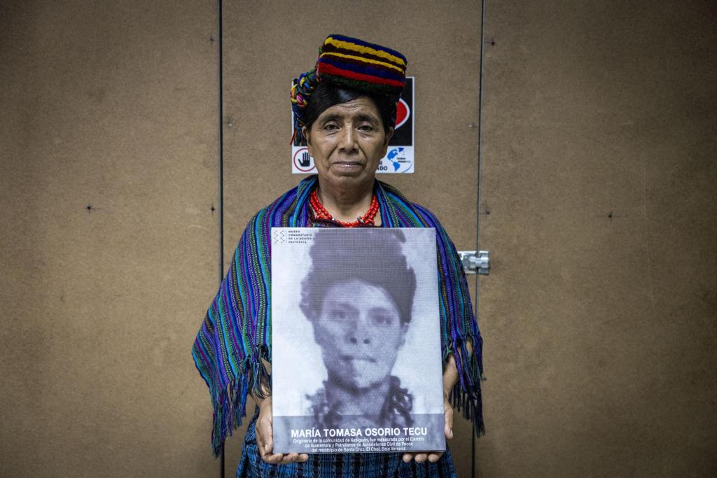 Máxima Garcia sobreviviente de la masacre del Rancho Bejuco posa hoy, con el retrato de su familiar masacrada, en Cuidad de Guatemala (Guatemala). EFE/Esteban Biba
