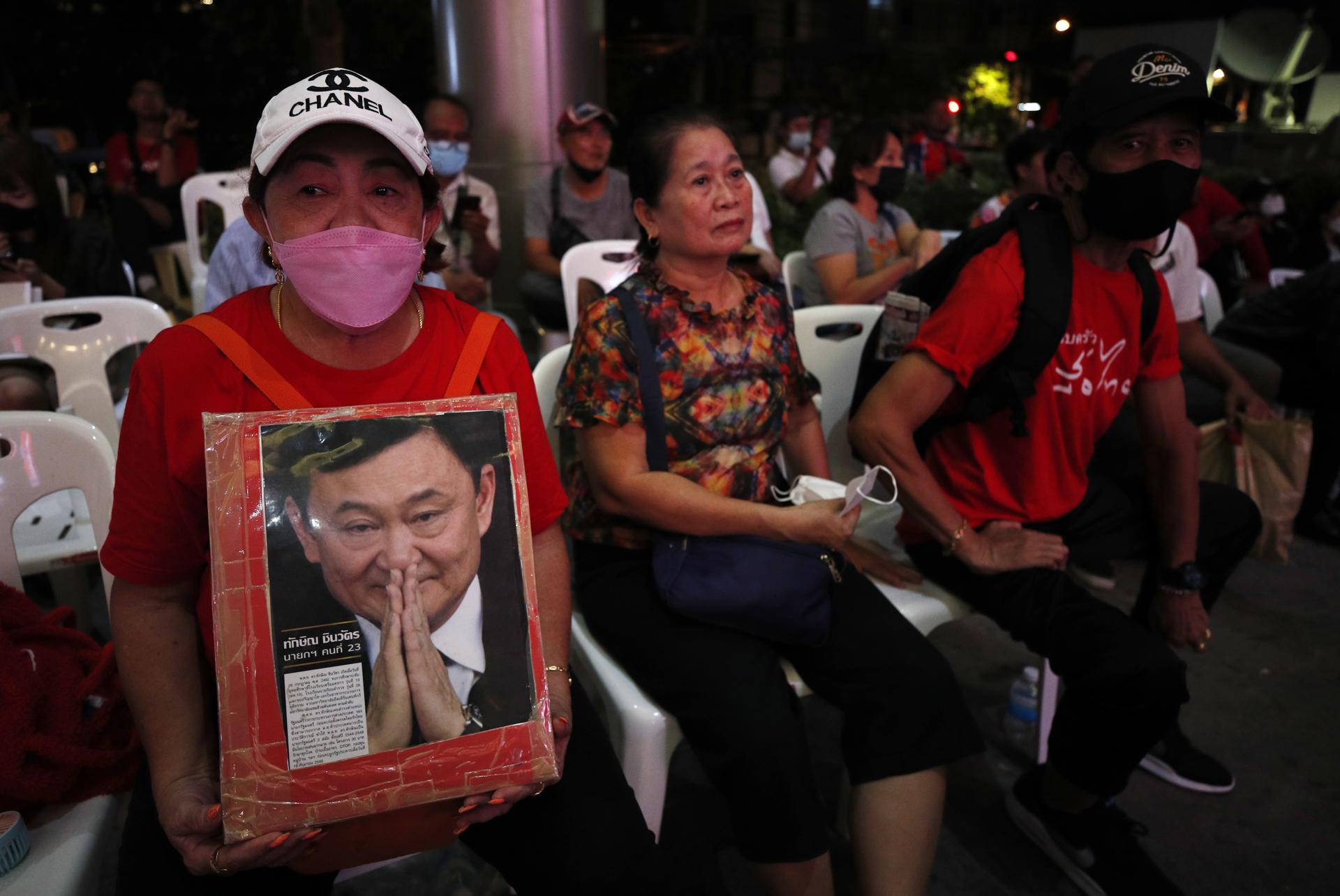 A supporter of Pheu Thai Party holds up a portrait of the former prime minister and founder of the party, Thaksin Shinawatra, while watching a television broadcast of the election vote counting after polls closed in the general election at the party's headquarters in Bangkok, Thailand, 14 May 2023. EFE-EPA FILE/RUNGROJ YONGRIT