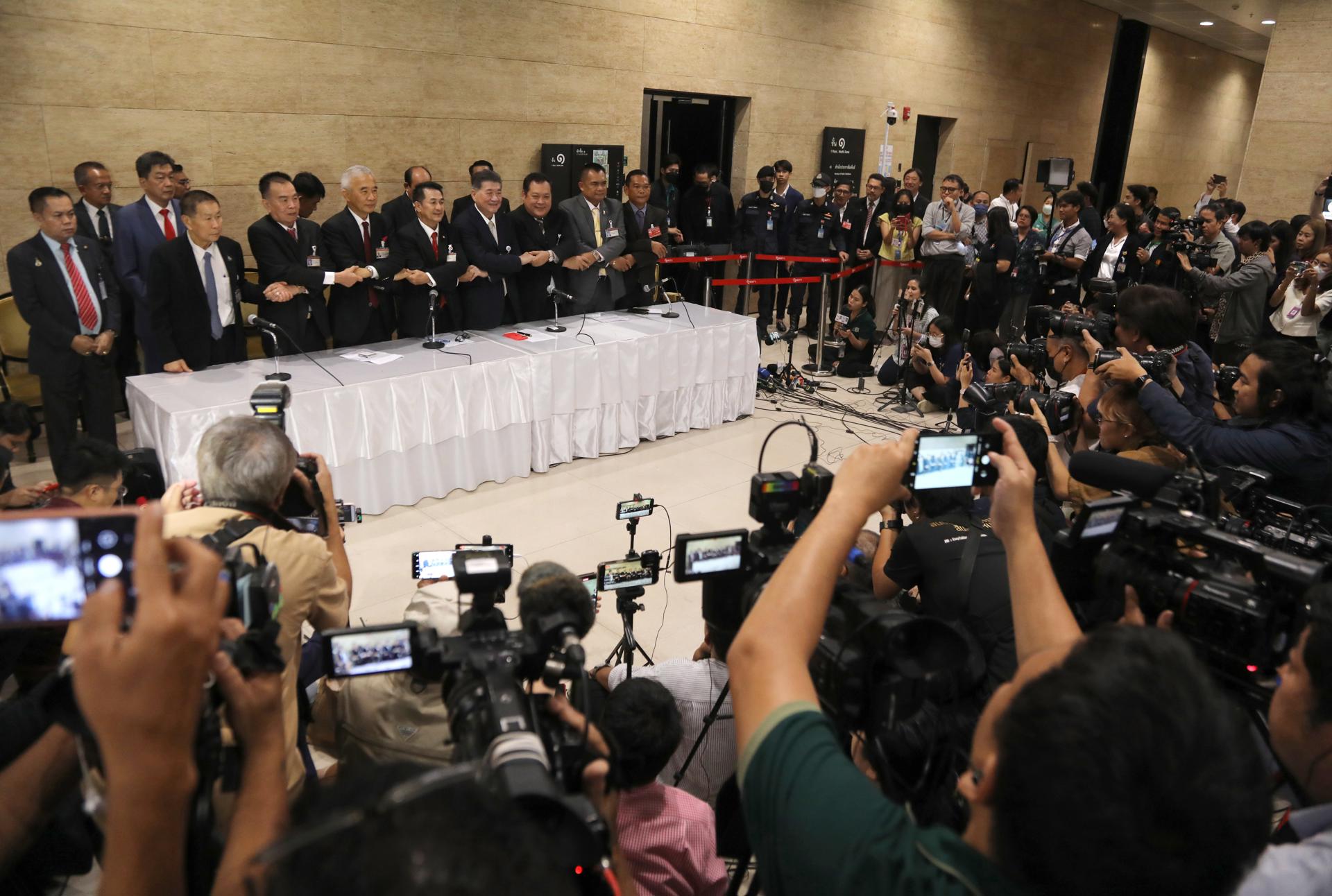 Pheu Thai Party leader Cholnan Srikaew (C) and members of six other parties hold hands after a press conference on the formation of a coalition government at the Parliament in Bangkok, Thailand, 09 August 2023. EFE/EPA/NARONG SANGNAK

