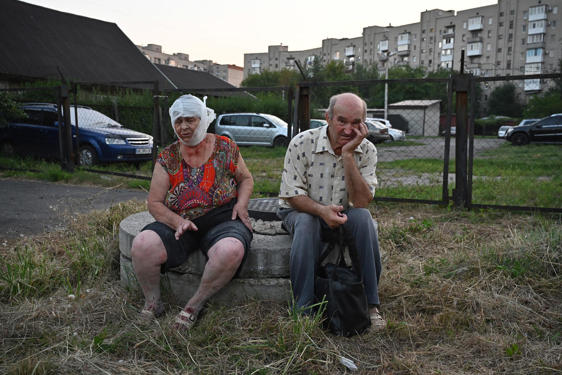 An injured woman and a man observe rescue works at a site where a rocket hit the city of Pokrovsk, Donetsk area, Ukraine, 07 August 2023. EFE-EPA/STANISLAV KRUPAR
