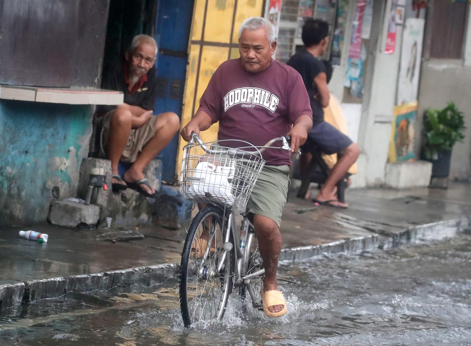 A Filipino villager rides a bicycle along a street covered by floodwater in Malabon city, Metro Manila, Philippines, 26 July 2023. EFE-EPA FILE/FRANCIS R. MALASIG