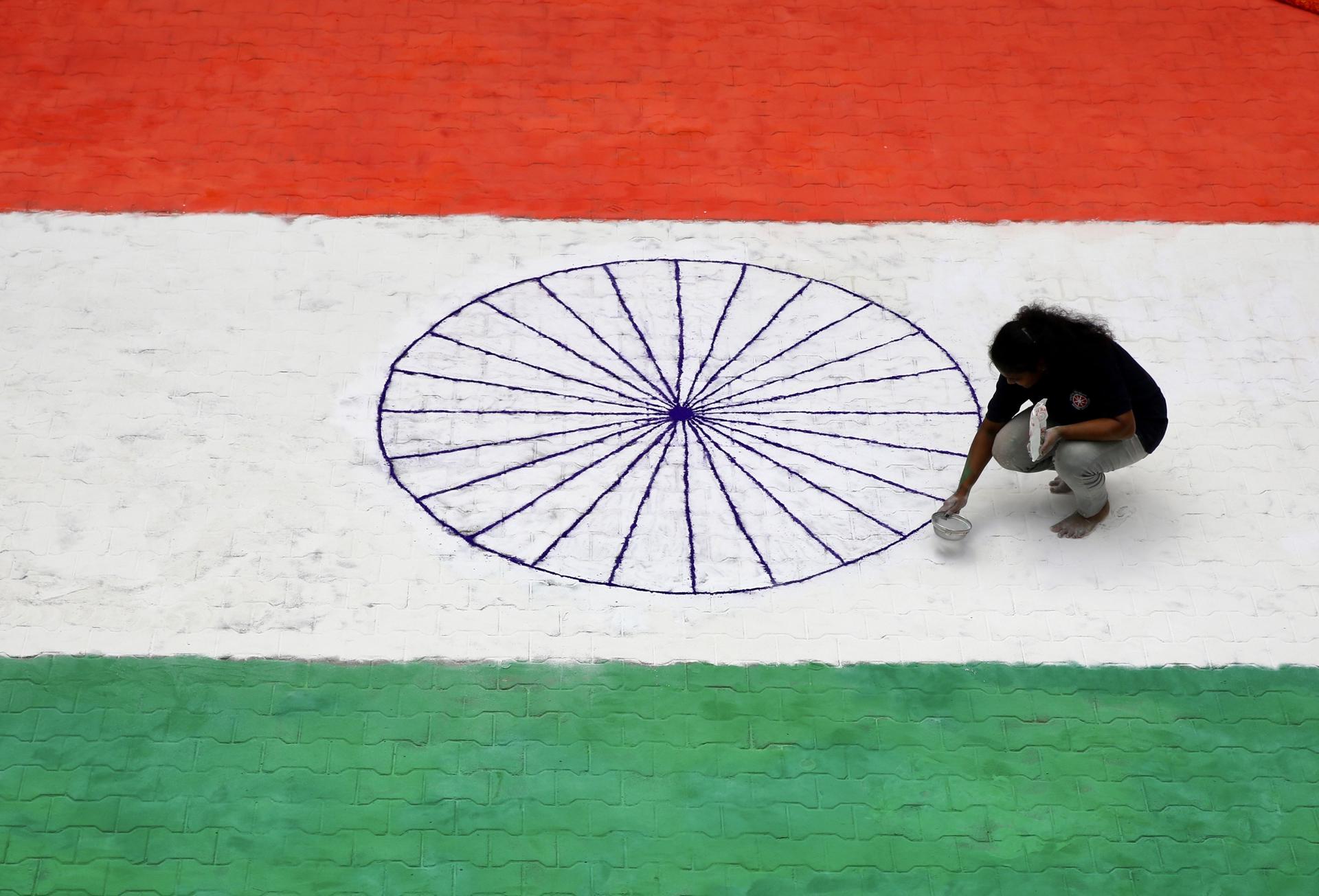 An Indian girl puts the finishing touches to a 50x40 foot, Indian tri-color flag made up of rangoli powder on the eve of Independence Day celebrations, in Bangalore, India, 14 August 2023. EFE-EPA/JAGADEESH NV
