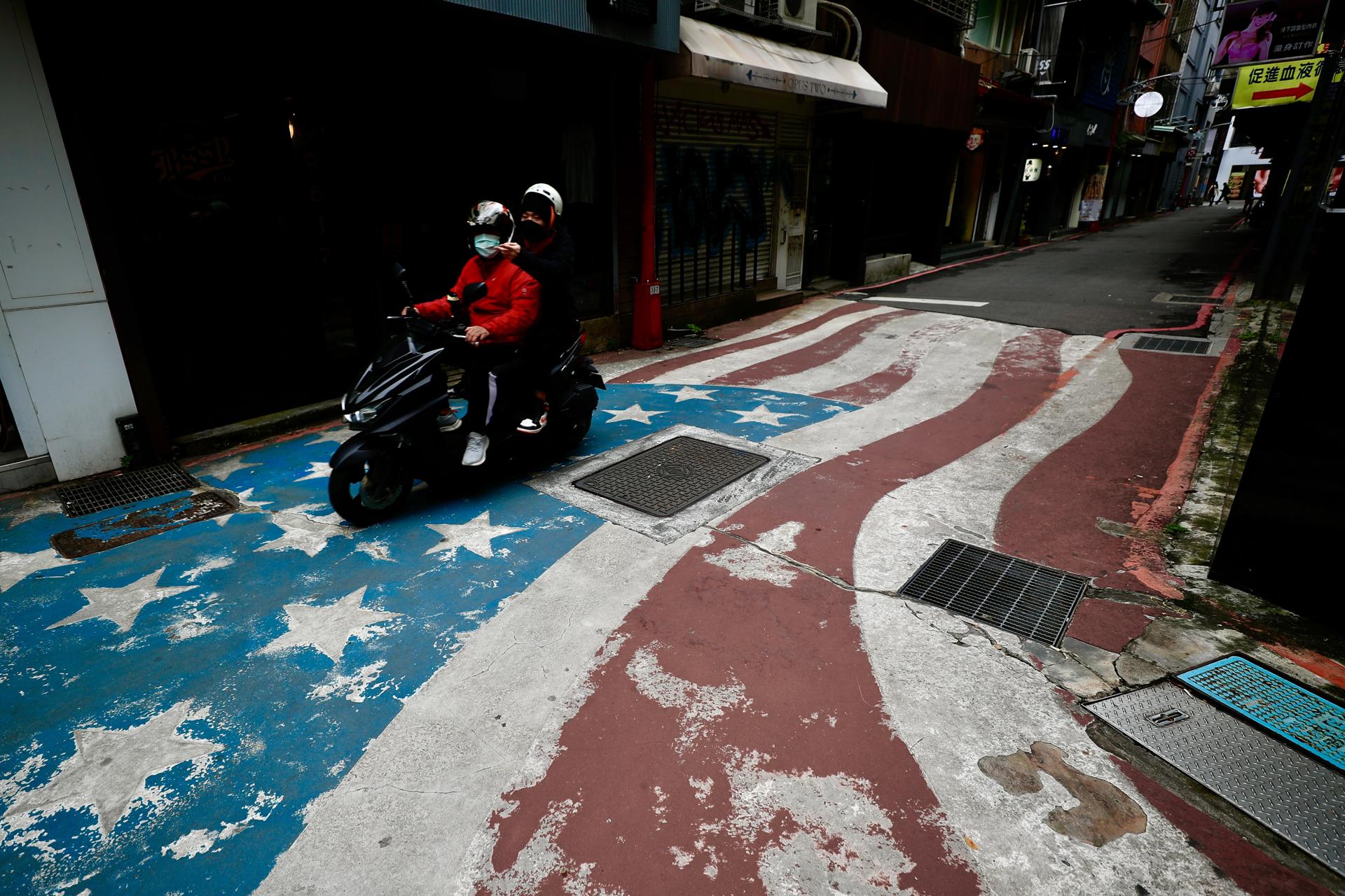 A motorist drives on an US flag pained on a street in Taipei, Taiwan, 24 November 2021. EFE-EPA FILE/RITCHIE B. TONGO
