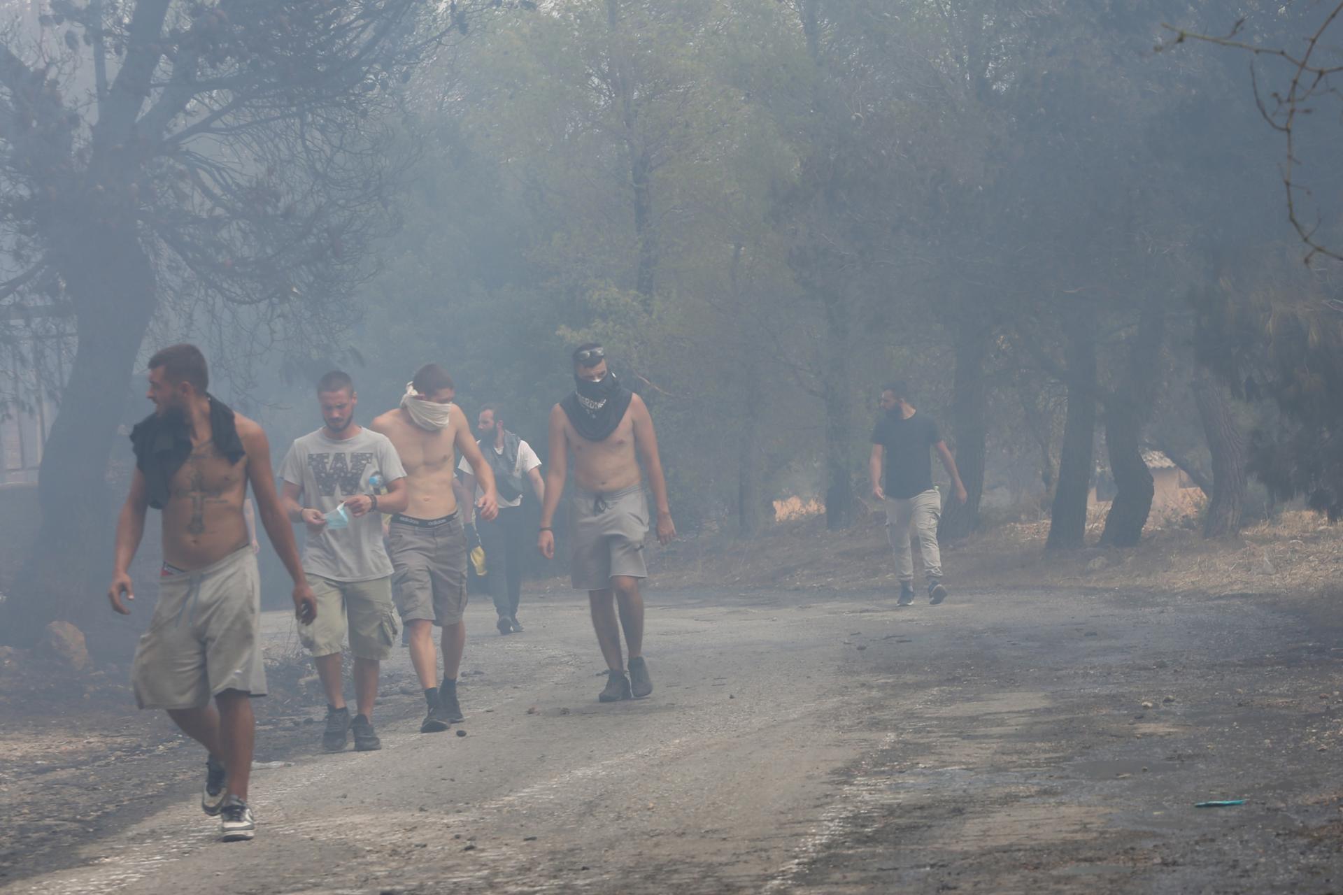 Residents walk through the smoke at Agia Paraskevi village near Acharnes, Attica, Greece, 23 August 2023. EFE/EPA/ALEXANDROS BELTES