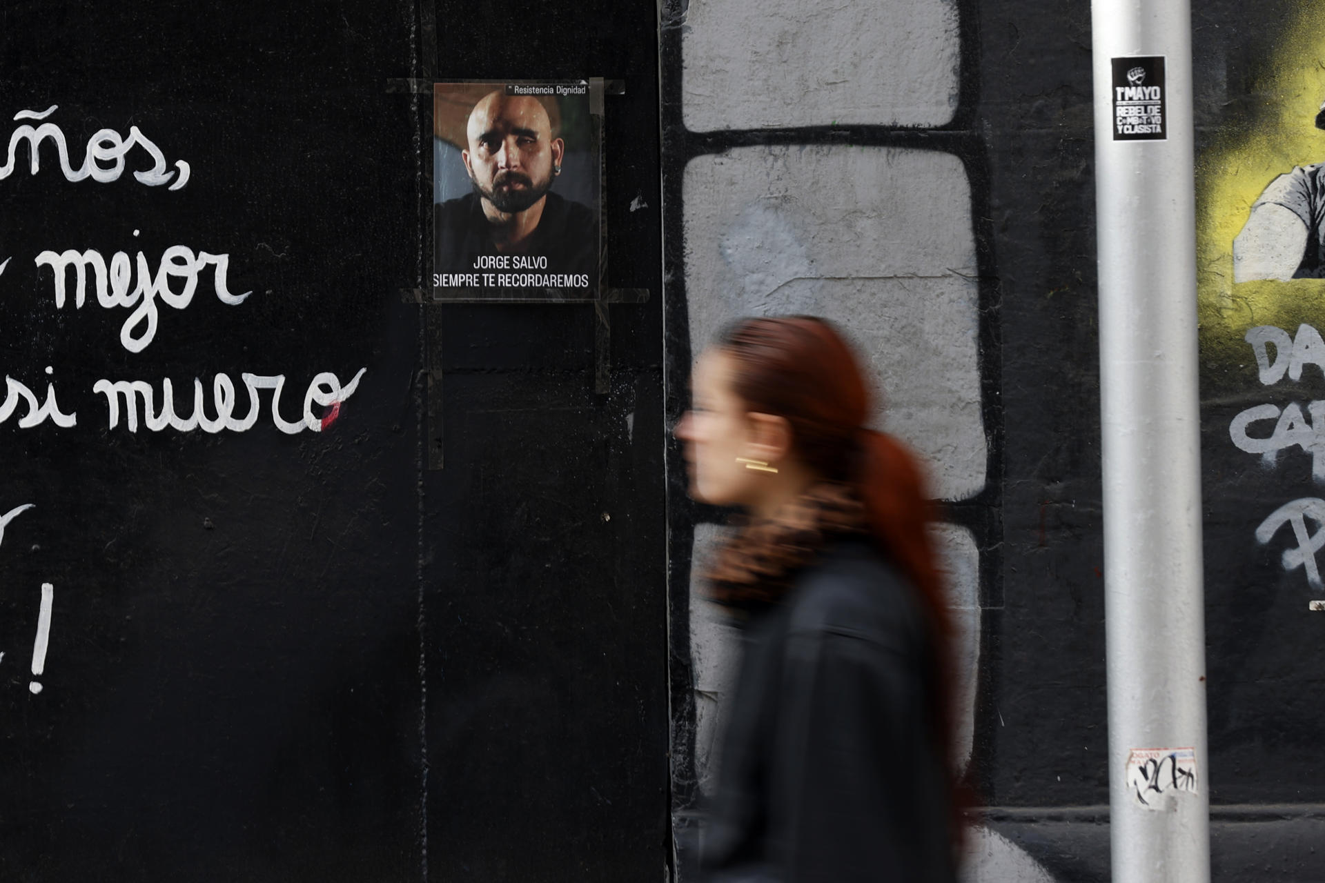 A woman walks past a photograph of Jorge Salvo, victim of a police-inflicted eye injury who took his own life, displayed on a building in Santiago on 26 July 2023. EFE/Elvis Gonzalez
