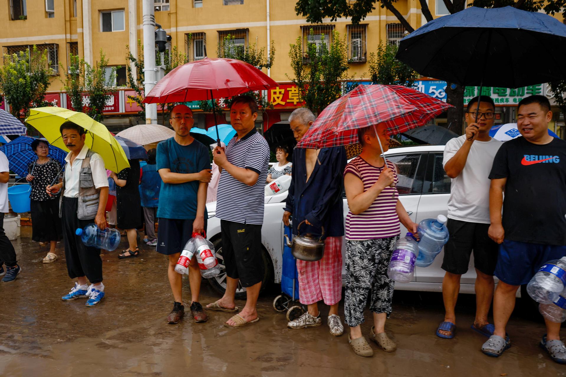 People lineup for water during a downpour in Mentougou District, west of Beijing, China, 01 August 2023. EFE-EPA FILE/MARK R. CRISTINO
