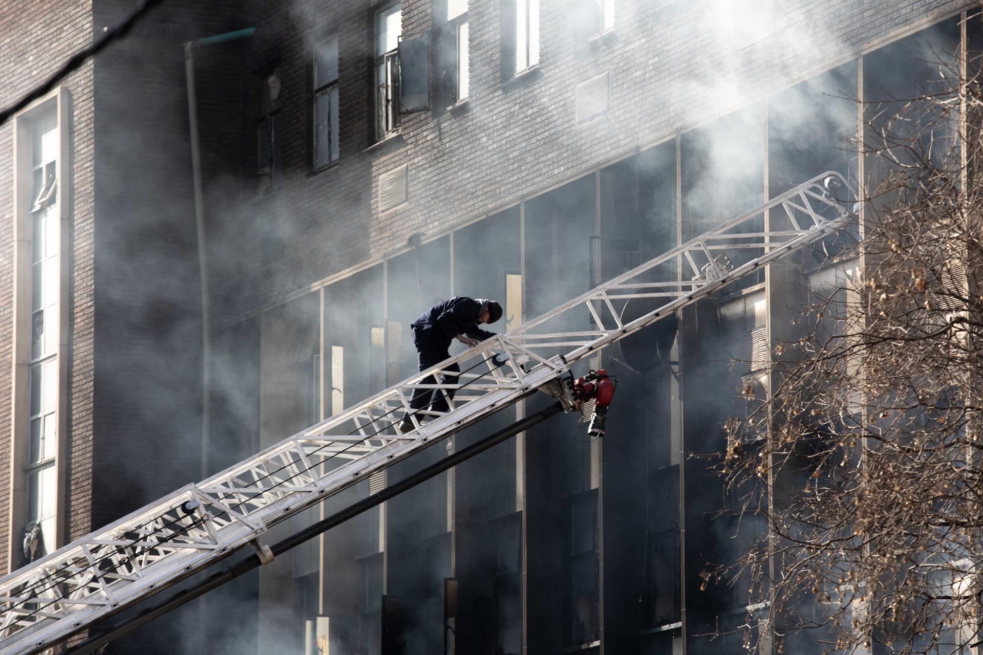 An emergency services member climbs a ladder at the site of a fire that broke out at a five-story building in the city center, in Johannesburg, South Africa, 31 August 2023. EFE-EPA/KIM LUDBROOK