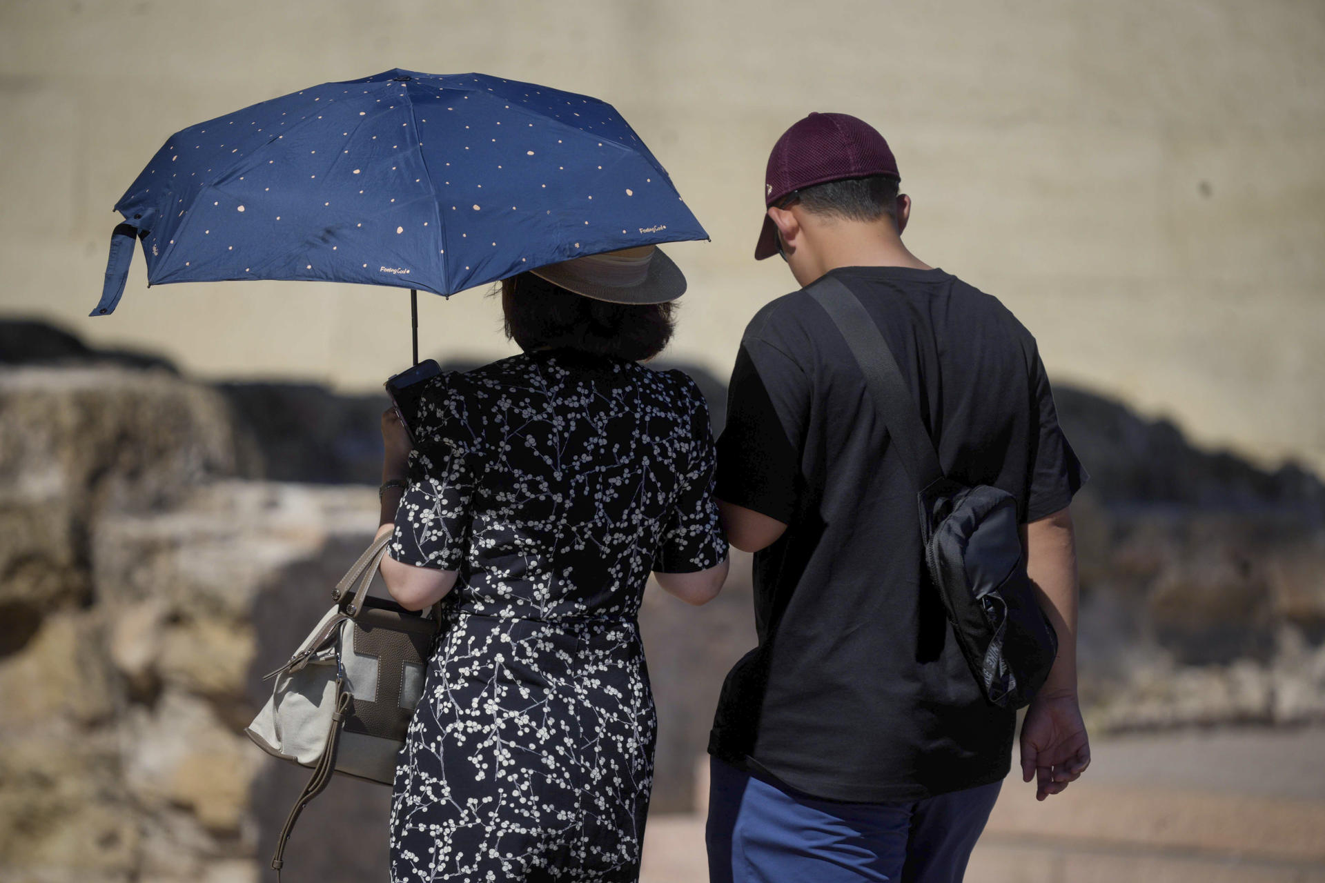 Una familia pasea por la judería protegidos del sol con un paraguas en Córdoba. EFE/Rafa Alcaide