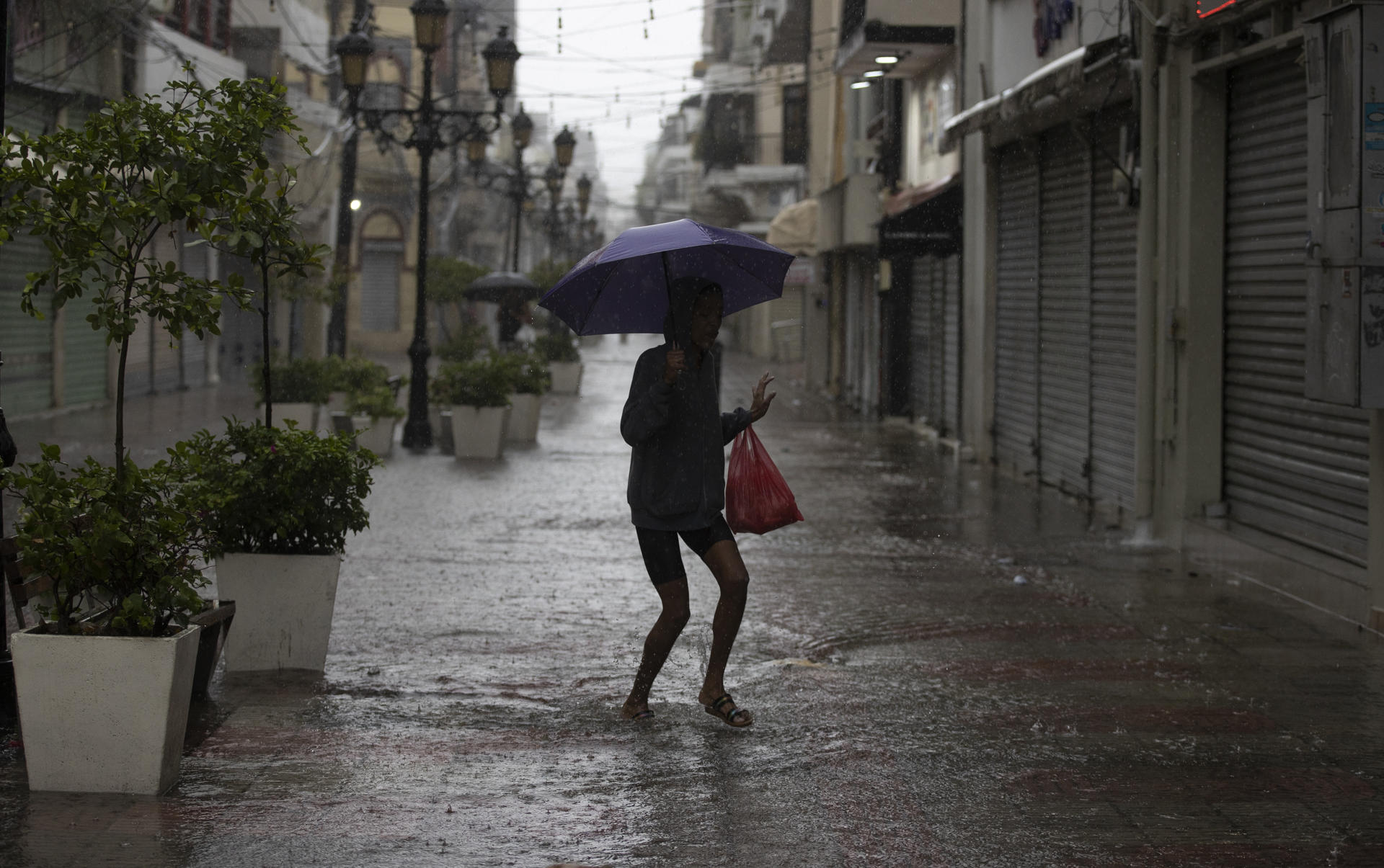 A person walks on a flooded street due to the passage of tropical storm Franklin, in Santo Domingo, Dominican Republic, 23 August 2023. EFE/Orlando Barría