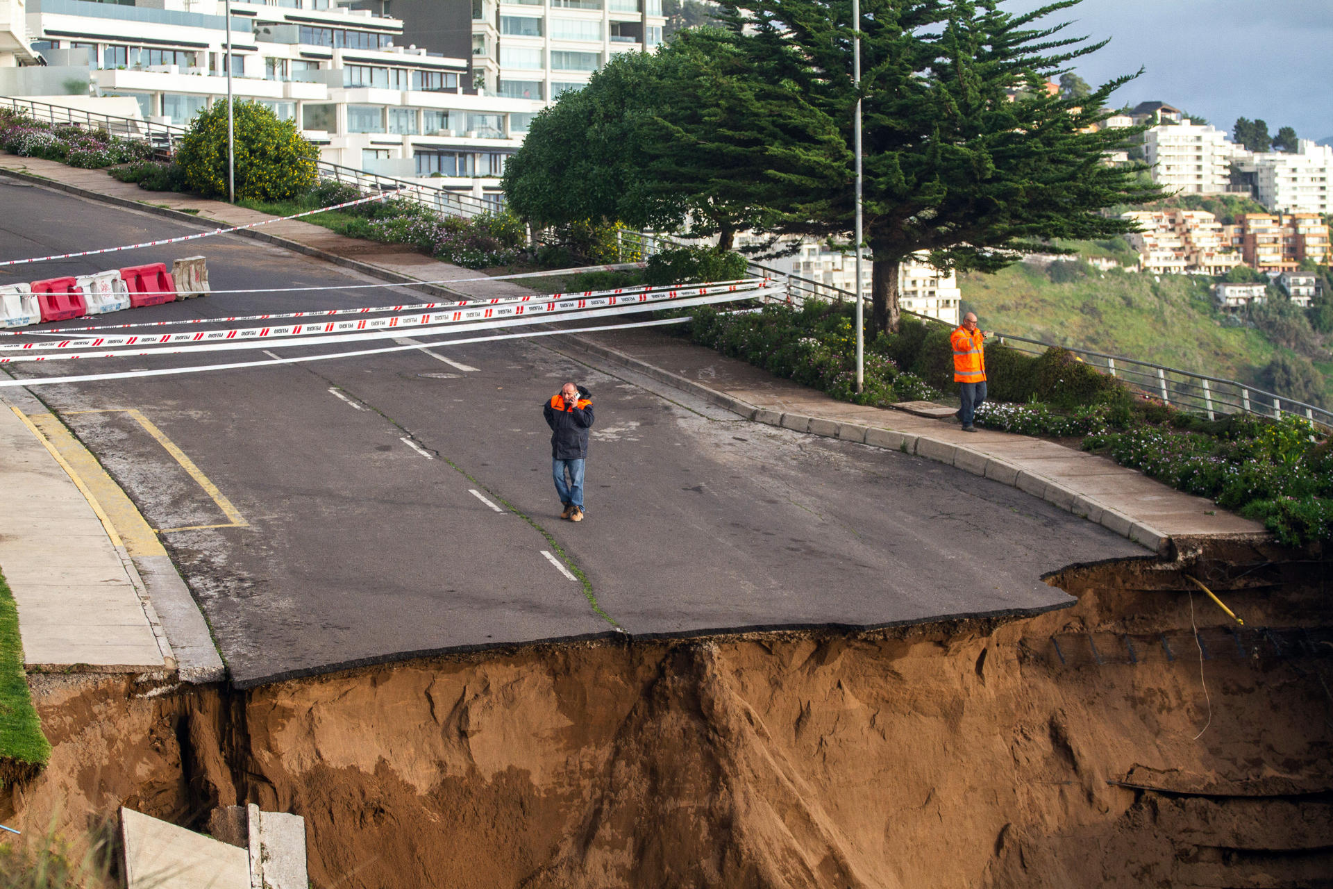 Fotografía que muestra una vía destruida frente a un edificio con riesgo de caída, consecuencia de un socavón debido a las fuertes lluvias en la zona, el 23 de agosto de 2023, en la ciudad de Viña del Mar (Chile). EFE/Cristóbal Basure